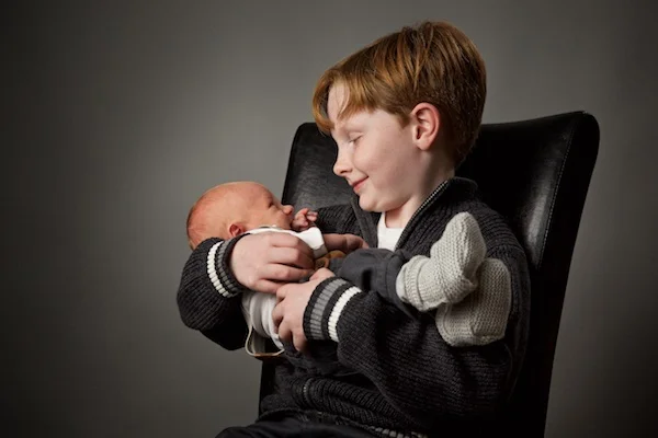 photo of boy holding baby