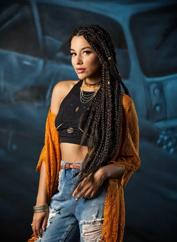 Stylish woman with long braided hair and orange shawl and torn jeans