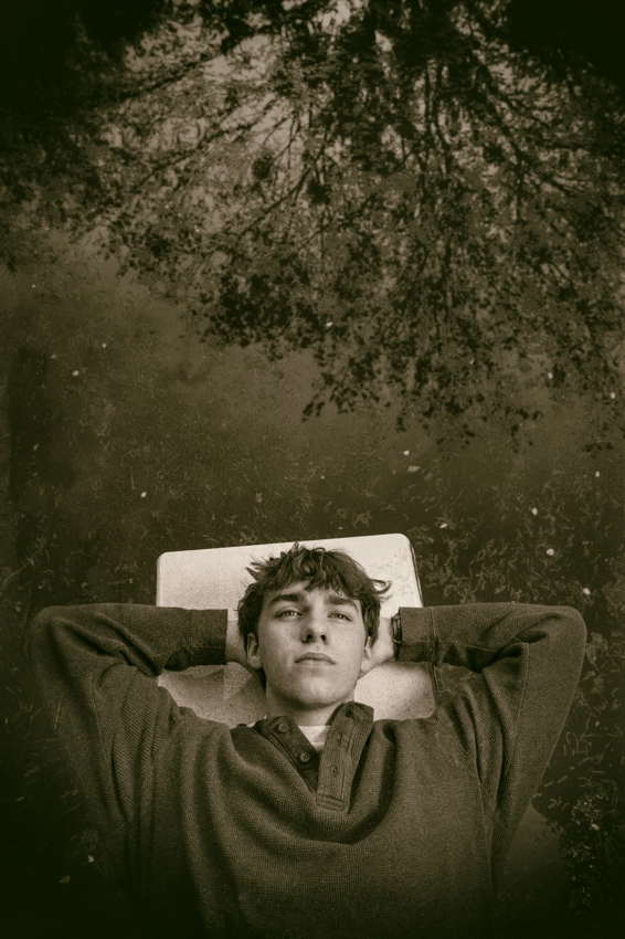 high school senior contemplating life laying on his back on a diving board