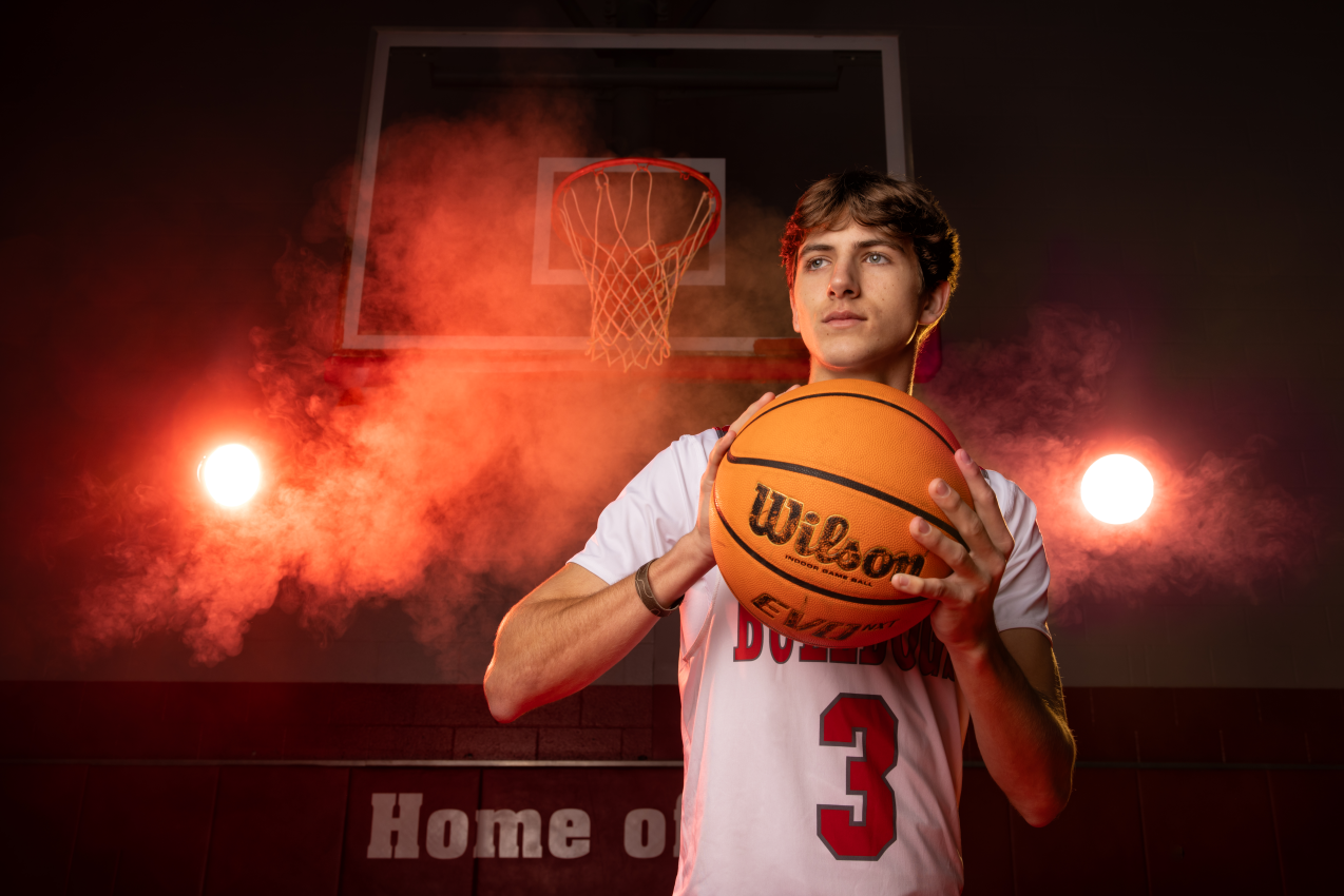 Senior photo young man in basketball uniform with basketball in a dramatic gym, Senior photography, Senior session
