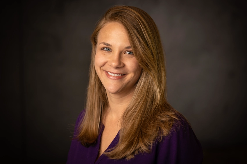 Woman in purple in front of a neutral background