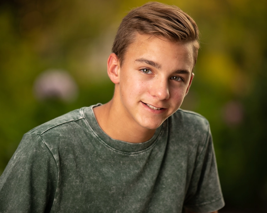 Teen boy in green shirt with greenery in background