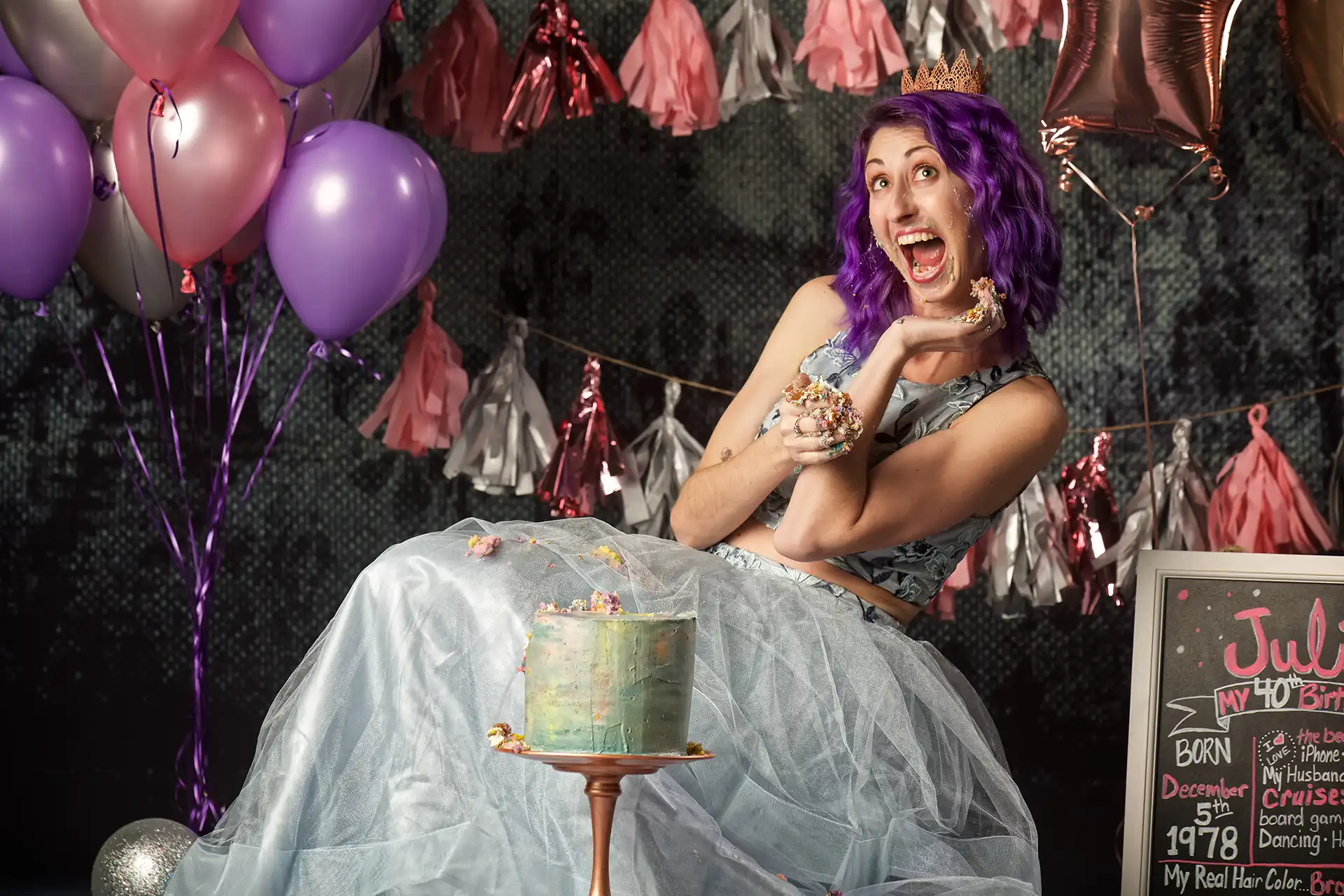 Woman in party dress wearing a crown laughing while smashing birthday cake. Tulsa photography
